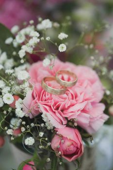 Gold wedding rings on a bouquet of fresh flowers.