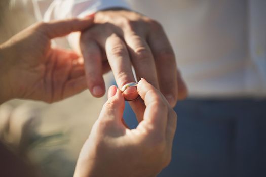 bride wears a ring on the groom's finger