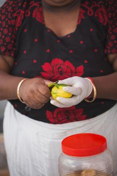 A woman peels mango at a wedding reception.