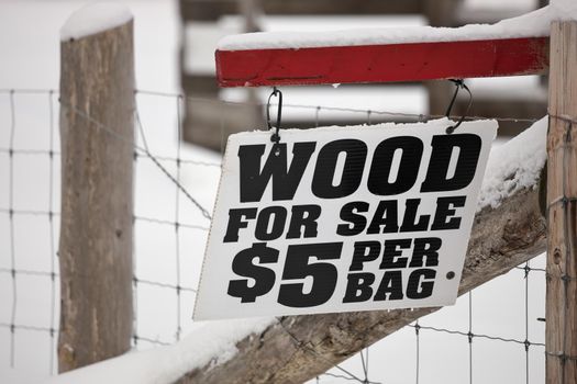A Firewood for Sale Sign hanging on a fence in a rural setting. High quality photo