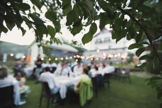 Wedding banquet outdoors during sunset. Tables with guests.