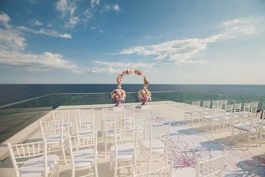 Wedding arch with fresh flowers on a sea background. Vases with fresh flowers.