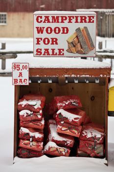 A Firewood for Sale Sign and bagged firewood in a rural setting. High quality photo