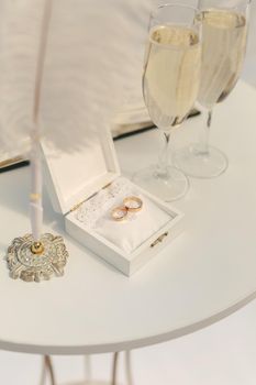 A box with wedding rings and gold sequins, champagne glasses, flowers.