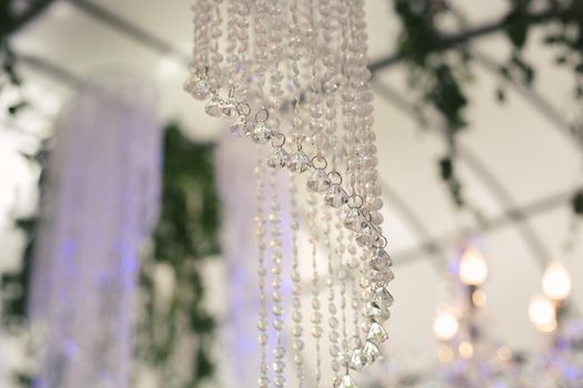 Beautiful luxurious romantic decor for a wedding celebration. The arch is decorated with draped fabric and a crystal chandelier.