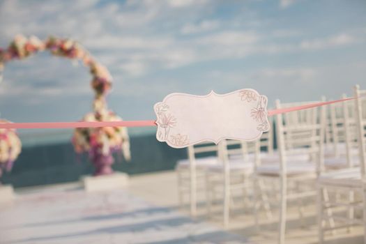 A sign on the backdrop of wedding arch and the sea.