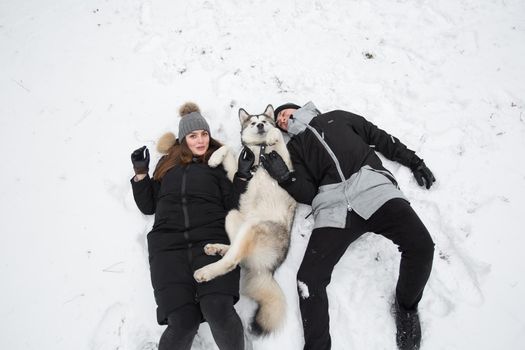 Beautiful family, a man and a girl in winter forest with dog. Play with the dog Siberian husky.