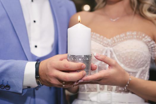 A candle in the hands of the newlyweds. Ignition of the family hearth at the wedding