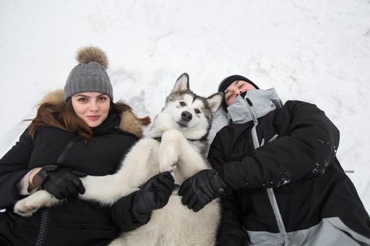 Beautiful family, a man and a girl in winter forest with dog. Play with the dog Siberian husky.