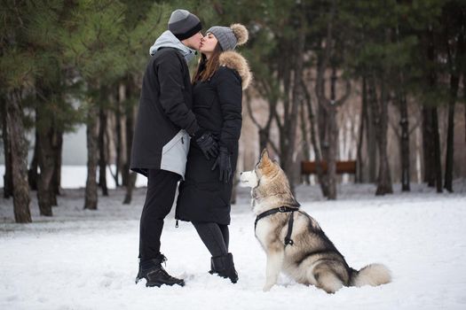 Beautiful family, a man and a girl in winter forest with dog. Play with the dog Siberian husky.