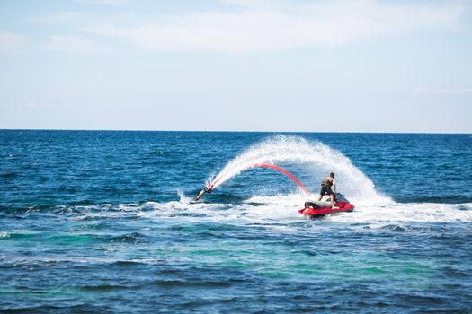 A rider on a flyboard in the ocean does difficult stunts