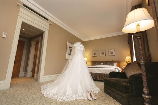 Chic wedding dress and veil on a mannequin in the bride 's gathering room.