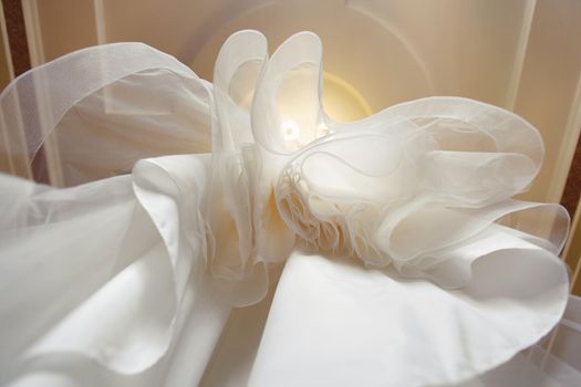 a view of a wedding dress from below with jagged edges, layers hanging from an iron rod detail on a chandelier