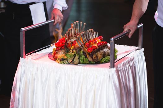 A waiter takes out a square of lamb at a wedding banquet.