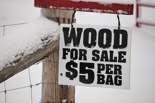 A Firewood for Sale Sign hanging on a fence in a rural setting. High quality photo