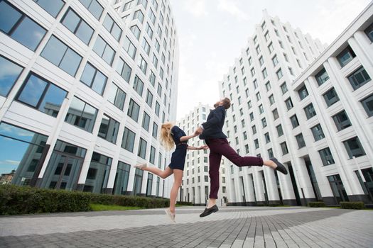 Man and woman are jumping on the background of the building of the business center.