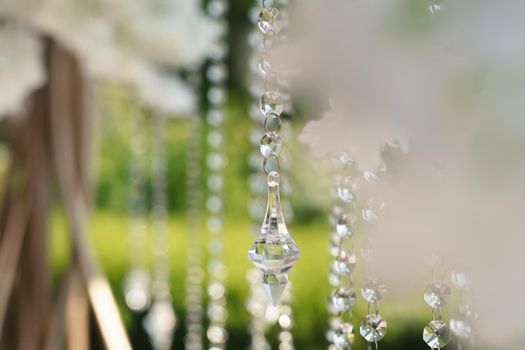 Details of the wedding ceremony made of fresh flowers, sparkling beads. Delicate and beautiful wedding decor for newlyweds.