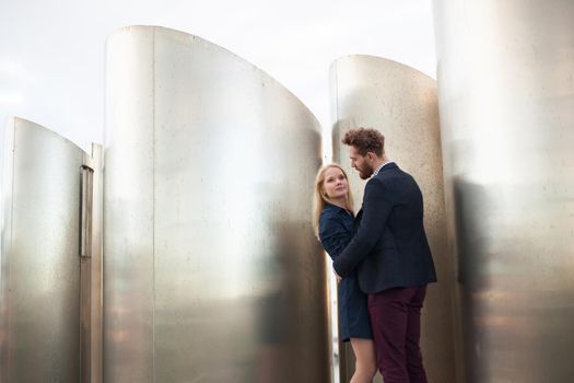 Man and woman pose in front of the large metal pipes