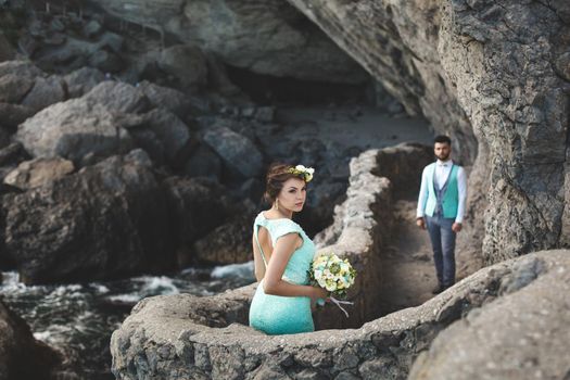 The bride and groom on nature in the mountains near the water. Suit and dress color Tiffany. Kiss and hug.