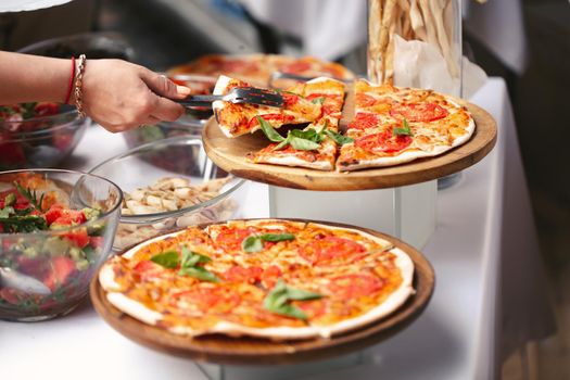 Self-service at the buffet. A variety of pizza and salads.