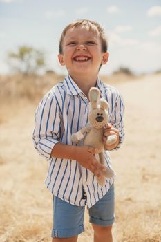 Happy boy holding a toy rabbit. Hare.