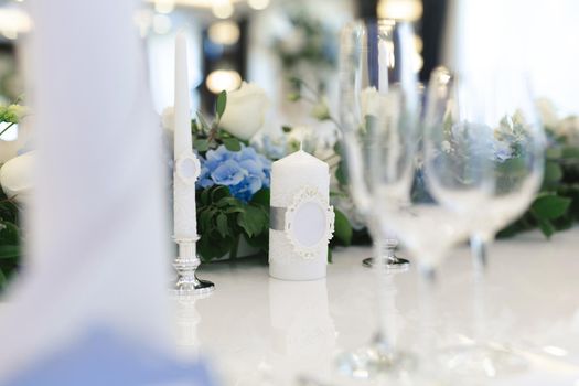 Wedding decor at the banquet. Flowers and candles with the initials of the bride and groom.