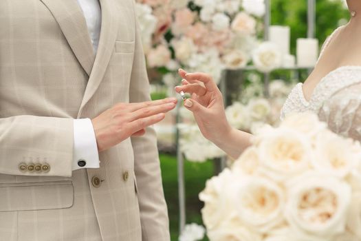 Wedding engagement rings. A married couple exchanges wedding rings at a wedding ceremony. The bride puts a ring on her groom's finger.