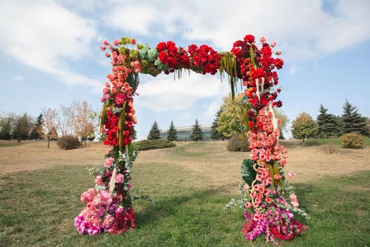 Autumnal wedding arch decoration of roses, apples, grape and pomergranate