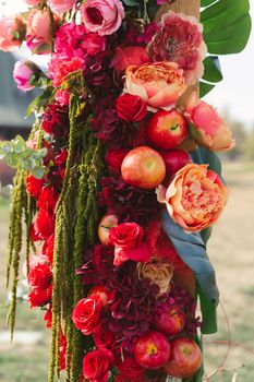 Autumnal wedding arch decoration of roses, apples, grape and pomergranate