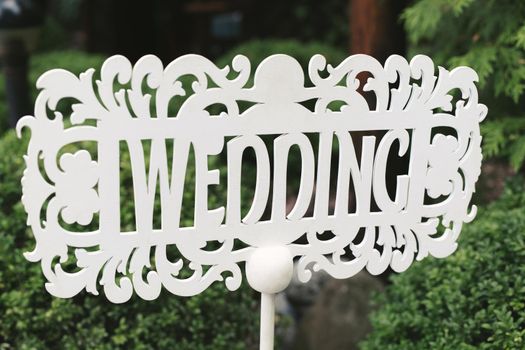 White wooden sign in the form of an arrow and a pointer with the inscription and letters