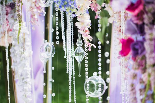 Details of the wedding ceremony made of fresh flowers, sparkling beads. Delicate and beautiful wedding decor for newlyweds.