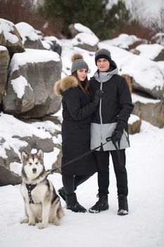 Beautiful family, a man and a girl in winter forest with dog. Play with the dog Siberian husky.