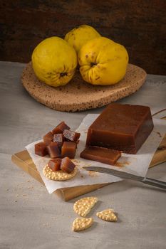 Marmalade in crackers on a kitchen counter with quinces on a cork tray.