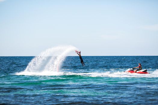 A rider on a flyboard in the ocean does difficult stunts