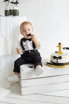 The first birthday of the child. One year with a cake. Child in a tuxedo