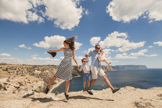 Happy family jumping together on top of a mountain