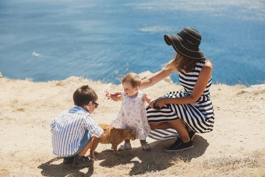 Happy family playing with a cat in nature.