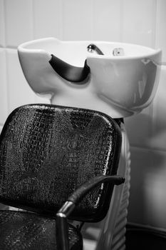 The black leather recliner next to the sink in the Barber shop. Black and white