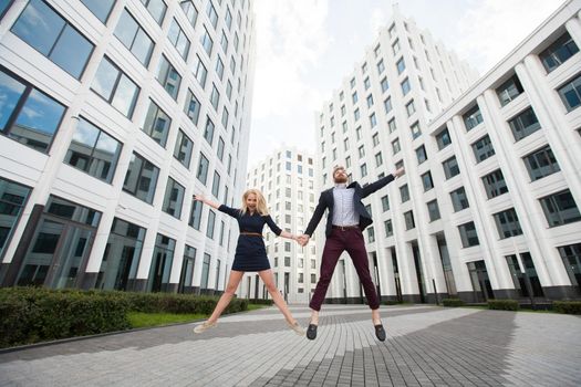 Man and woman are jumping on the background of the building of the business center.