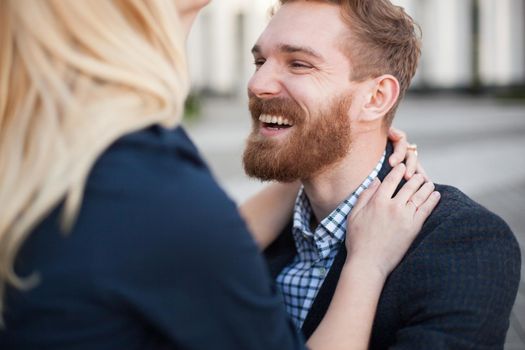 The man with the beard laughs, hugging his woman