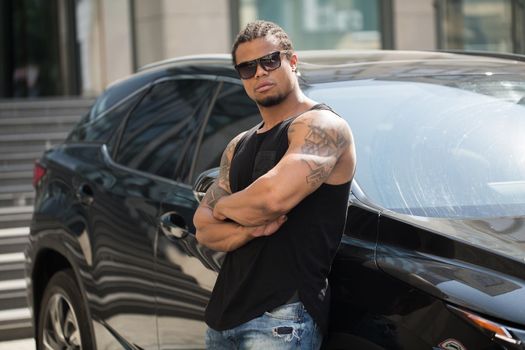 Stylish black man, standing beside his fancy car