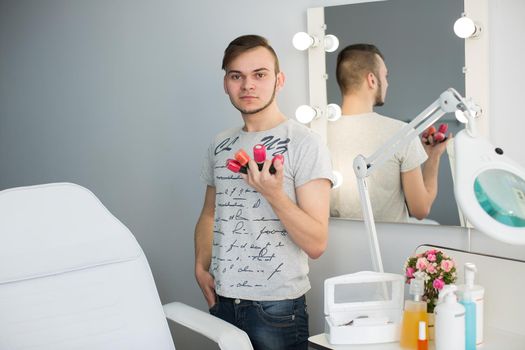 Male manicurist is holding a nail Polish.