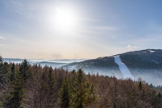 Foggy view of Beskid Sadecki mountain range with ski slope of Jaworzyna Krynicka in Poland