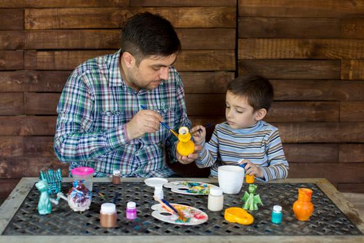 Father and son in the Studio of paint a vase.