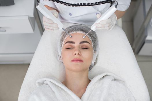 Macro close up portrait of woman having cosmetic galvanic beauty treatment in spa.Therapist applying low frequency current with electrodes on face