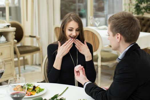 Marriage proposal at a restaurant. A man puts a ring on a woman's finger
