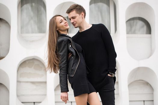 young sexy couple in black clothes posing with a background on the white wall