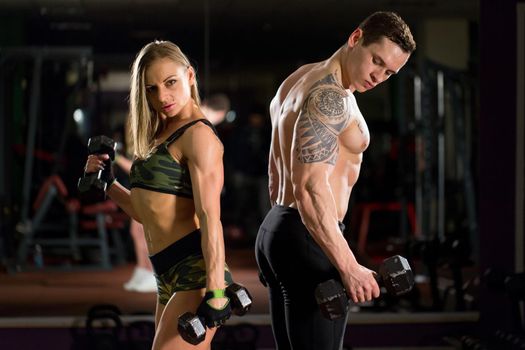 Beautiful young sporty sexy couple showing muscle and workout in gym