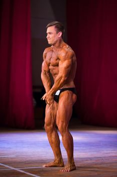 athlete bodybuilder demonstrates abdominal muscles and chest at competitions