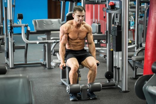 Athletic strong bodybuilder execute exercise in sport gym hall on the uneven bars